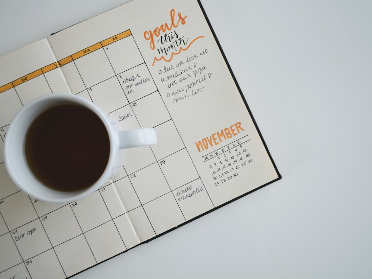Paper planner calendar beside a cup of coffee